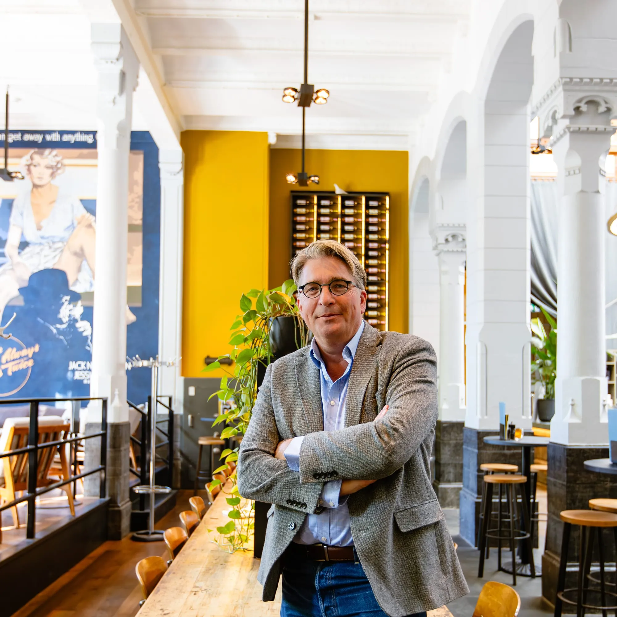 Derk Jan Lange in een restaurant, met zijn armen over elkaar en een vriendelijke blik naar de camera